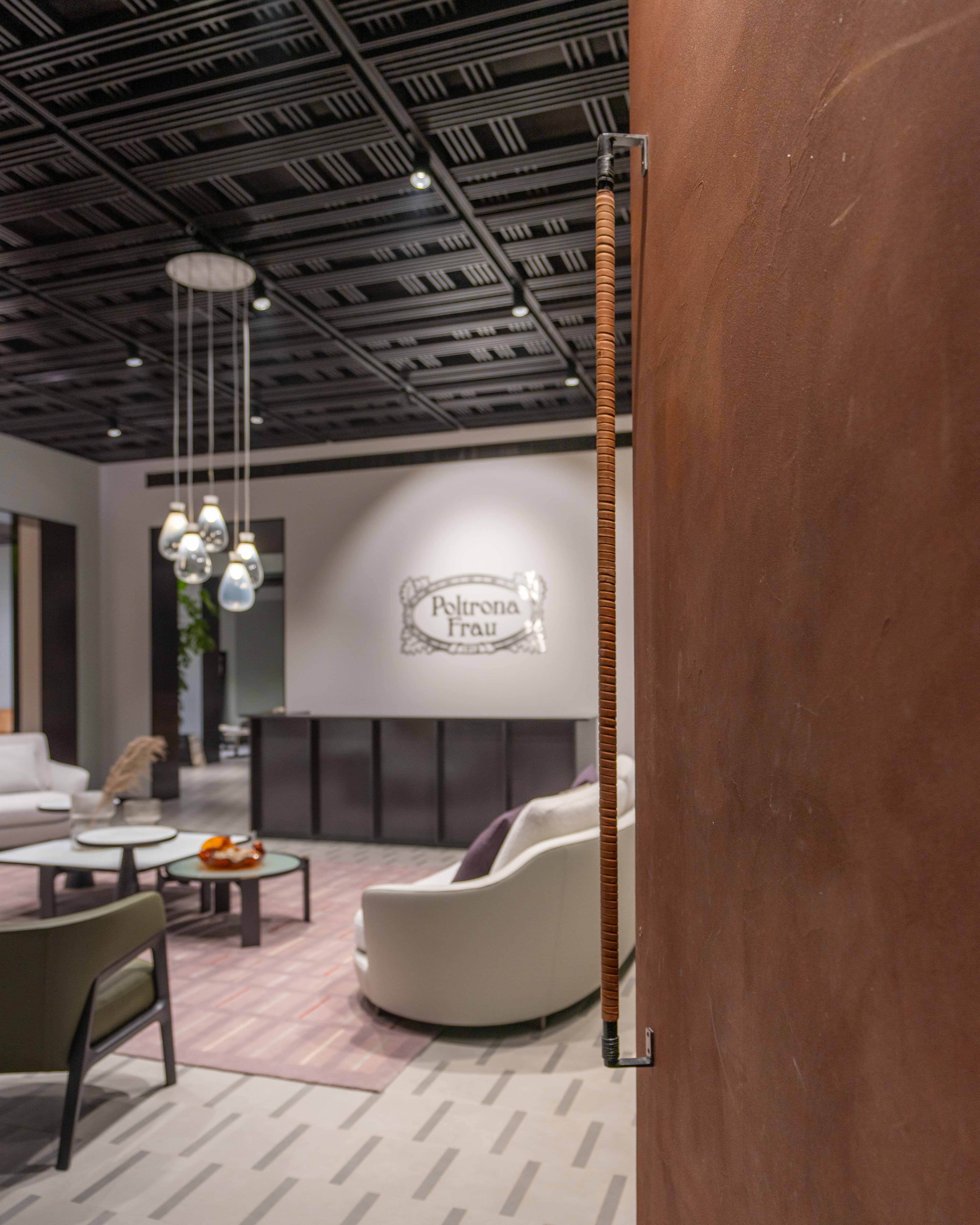 Poltrona Frau gallery vignette at Artyk — a curved lounge chair beside a corten-toned partition